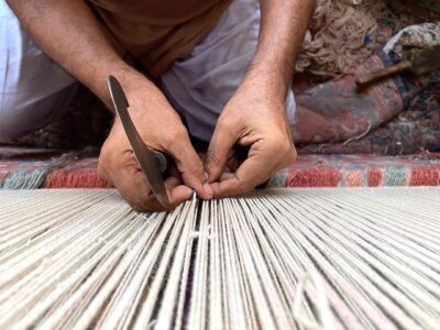 Artisans weaving intricate patterns into handmade rugs, showcasing craftsmanship, tradition, and cultural heritage.